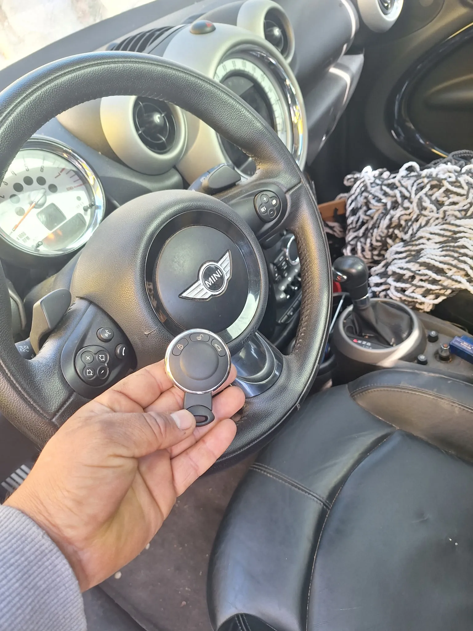 A car key next to a MINI Cooper steering wheel.
