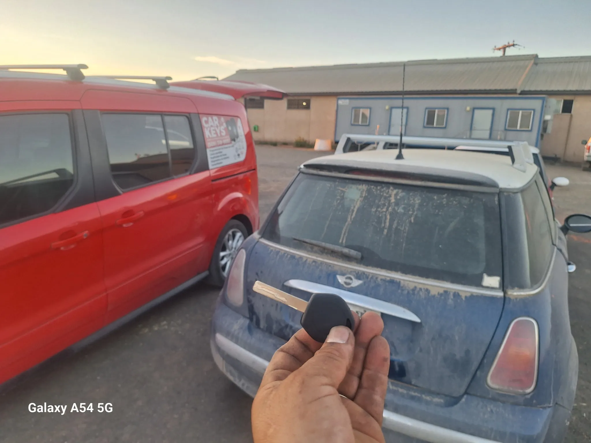 A car key in front of a blue MINI Cooper.